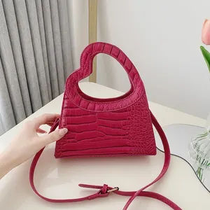 Fuchsia crocodile embossed handbag with heart-shaped cutout handle and shoulder strap
