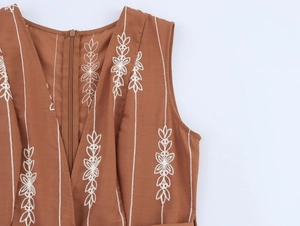 Détail du col en V avec broderie et fermeture éclair invisible sur la robe marron
