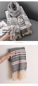 Detail of herringbone knit scarf with soft pink stripes and elegant fringe tassels