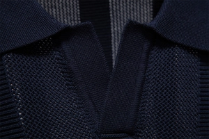 Macro shot of navy knit polo neckline showing refined hollow knit texture and V-neck detail