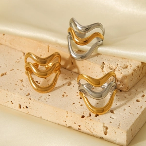 Polished wavy multi-layer stainless steel rings in gold and silver on travertine