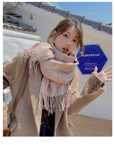 Detail of pink and khaki plaid scarf with long tassels paired with camel wool coat