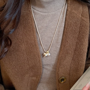Vue détaillée du collier vintage zircon cheval perle porté sur un manteau et un pull