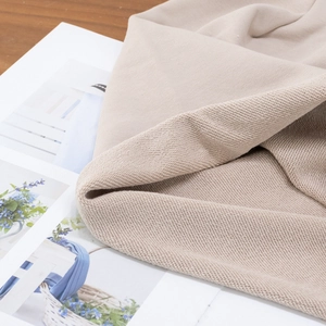 Macro shot of soft beige knitted terry fabric showing fiber texture and folded material