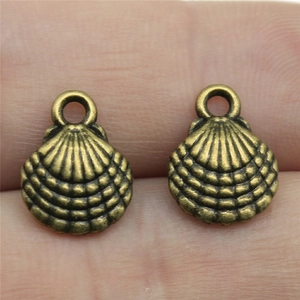 Close-up of two bronze shell pendants held between fingers showing detailed metal texture