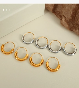 Detailed close-up of thick gold and silver hoop earrings on a textured paper backdrop