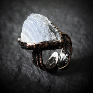 Macro detail of vintage bronze feather ring featuring a natural triangle agate stone