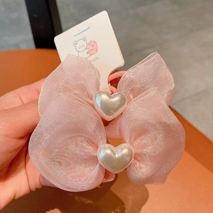 Close-up of pink mesh bow hair ties with pearl heart charms on a cartoon card