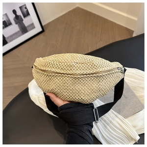 Detail of hand-woven straw chest bag in beige with adjustable black strap and zipper
