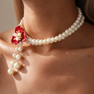 Detail of vintage double-layer pearl necklace featuring a red flower with pearl tassels