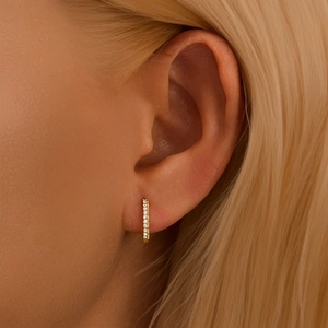 Detailed close-up of a twisted gold 925 silver hoop earring with clear crystals on ear