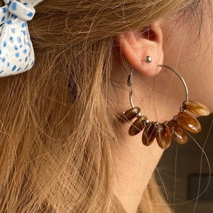 Close-up of amber beaded geometric hoop earring worn by a model in a retro style