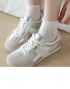 Gros plan de baskets en daim beige portées avec des chaussettes en dentelle Mary Jane
