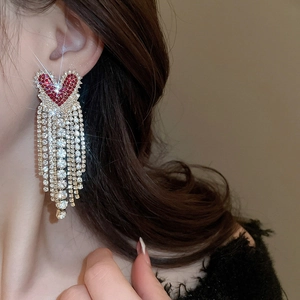 Detail of red heart tassel earrings with sparkling rhinestones on a female model