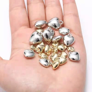 Macro view of gold and silver heart-shaped CCB beads held in hand for scale and detail