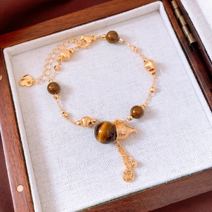 Detail of tiger eye bead bracelet with a hollow gourd pendant and vintage gold accents