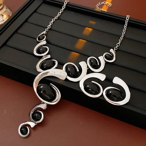 Macro detail of silver geometric necklace with black oval gemstones on a jewelry display
