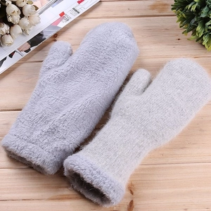 Close-up of gray plush mittens with thickened fleece cuffs on a wooden background