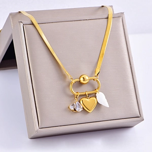 Gold necklace with heart, shell and zircon pendants displayed on a jewelry box cover