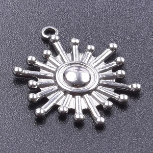Macro shot of silver sun-shaped pendant with radial lines and central sphere detail