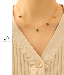 Close-up of gold stainless steel necklace with five colorful teardrop stones on a model