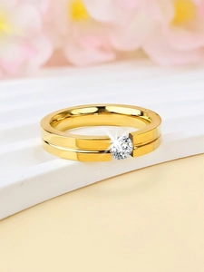 Macro shot of a 4mm gold titanium ring with a centered round zircon on a floral backdrop