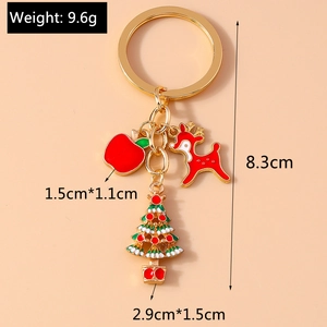 Detailed view of Christmas keychain with elk, apple, and tree charms on a pink background