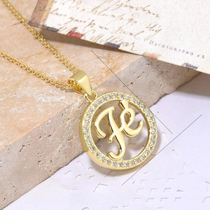 Macro shot of 18K gold plated copper necklace pendant with FE letter and zircons