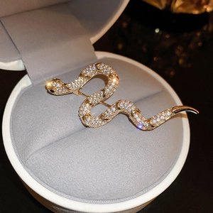 Close-up of gold-plated snake brooch with cubic zirconia in a white jewelry gift box