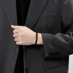 Close-up of a black beaded leather bracelet worn on a wrist with a dark suit