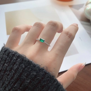 Detailed view of emerald-cut green gemstone ring with pavé moissanite band on hand
