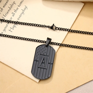 Detail of black stainless steel dog tag necklace featuring a textured American flag and letter A