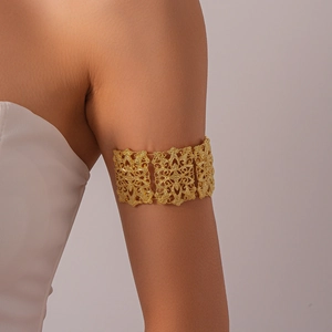 Détail du motif floral ajouré sur un large bracelet de bras vintage doré de style bohème