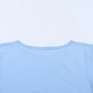 Détail macro du col rond et des coutures de finition d'une robe en maille bleu clair