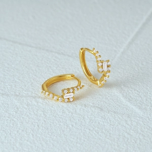 Detail of gold-plated silver hoops featuring baguette and round zircon stone settings