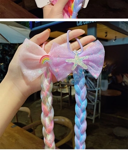 Detail of kids glitter mesh bows with rainbow star charms and colorful braided hair extensions