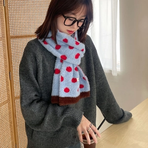 Soft blue plush scarf with red polka dots and brown trim worn by a model in soft lighting