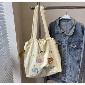 Detail of off-white canvas tote bag featuring embroidered puppy and colorful letters