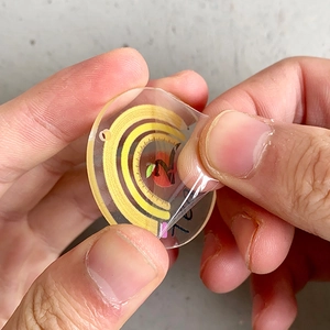 Acrylic school-themed earrings with rainbow and apple patterns showing protective film removal