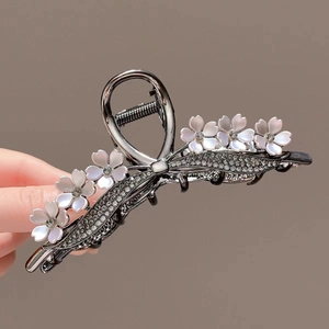 Detail of metal flower hair claw with shimmering petals and sparkling rhinestones