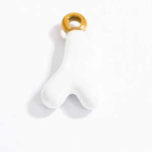 Dettaglio macro di un ciondolo astratto bianco in ceramica con anello dorato