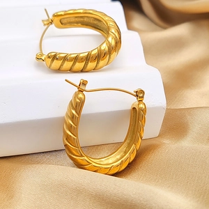 Detailed view of gold twisted hoop earrings with elegant spiral texture on white steps