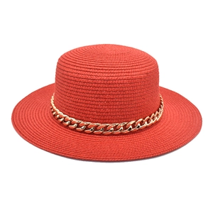 Détail d'un chapeau de paille rouge à toit plat avec une chaîne en acrylique doré