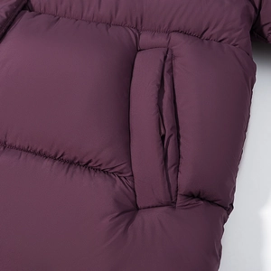 Vista dettagliata della tasca laterale su un cappotto invernale imbottito magenta