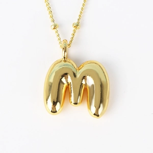 Close-up of a polished golden bubble letter M pendant on a fine link necklace chain