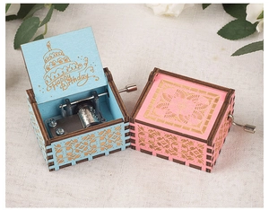Detail of pink and blue hand-cranked wooden music boxes with intricate carvings and flowers