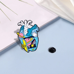 Detail view of Van Gogh heart brooch with enamel space scene and black rubber clutch