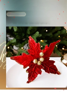 Détail d'un poinsettia en velours rouge avec bordures dorées sur un sapin de Noël