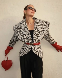 Detail of zebra print jacket paired with red leather gloves and heart-shaped handbag