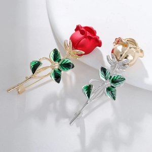 Exquisite rose brooches in red matte and gold finishes with green enamel leaf detailing